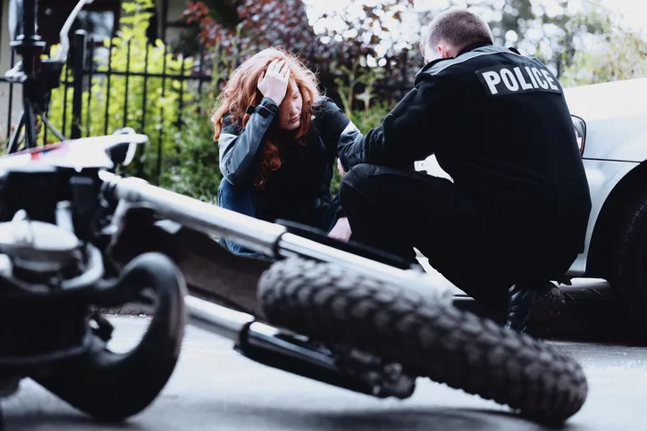 Policeman interviewing a dazed driver of a motorbike after a crash