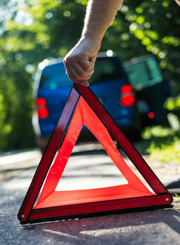 Motorist holding a warning triangle to signal a car accident ahead.